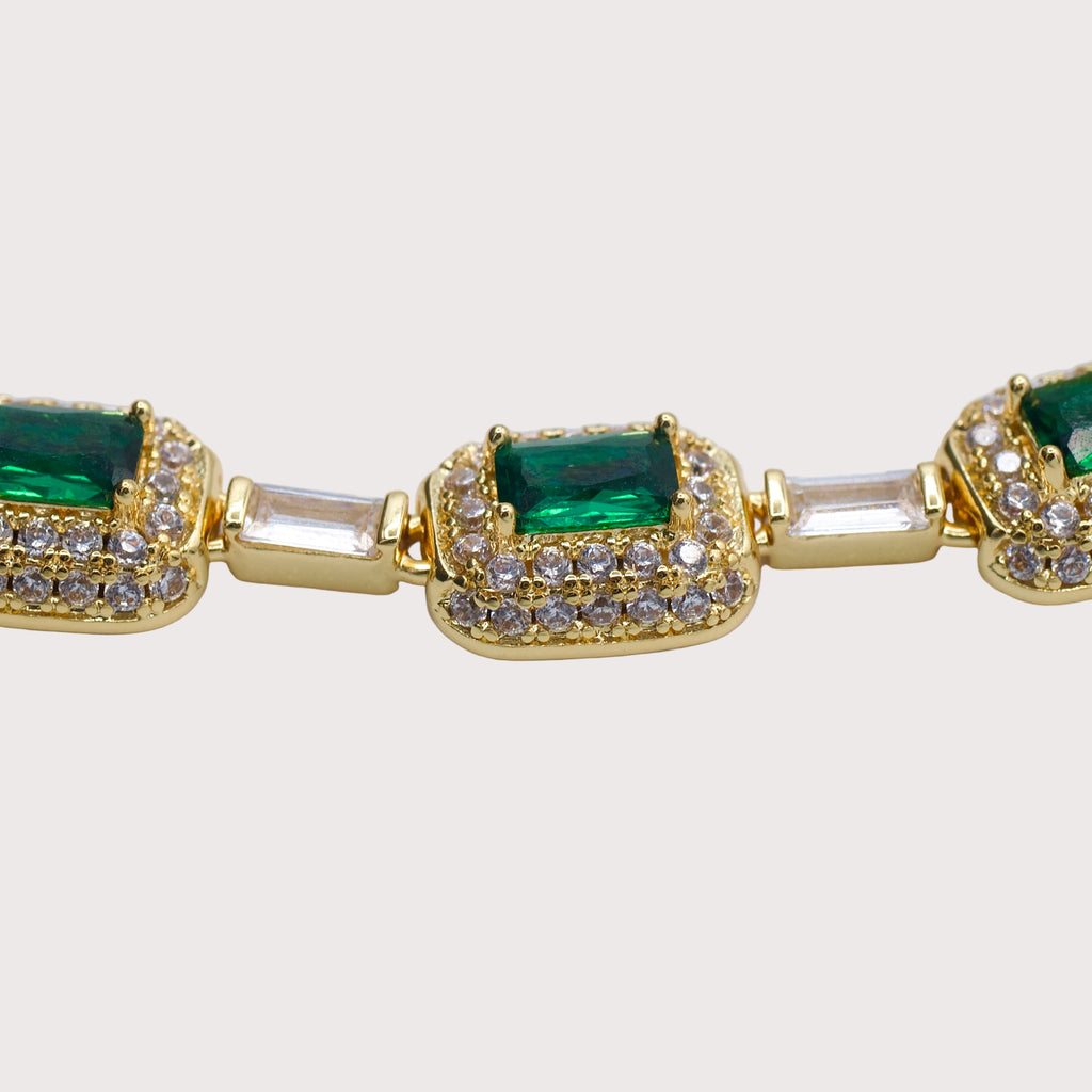 Gold bracelet with emerald and clear gemstones on a light gray background  - Verdeza Bracelet - JCollins Jewelry