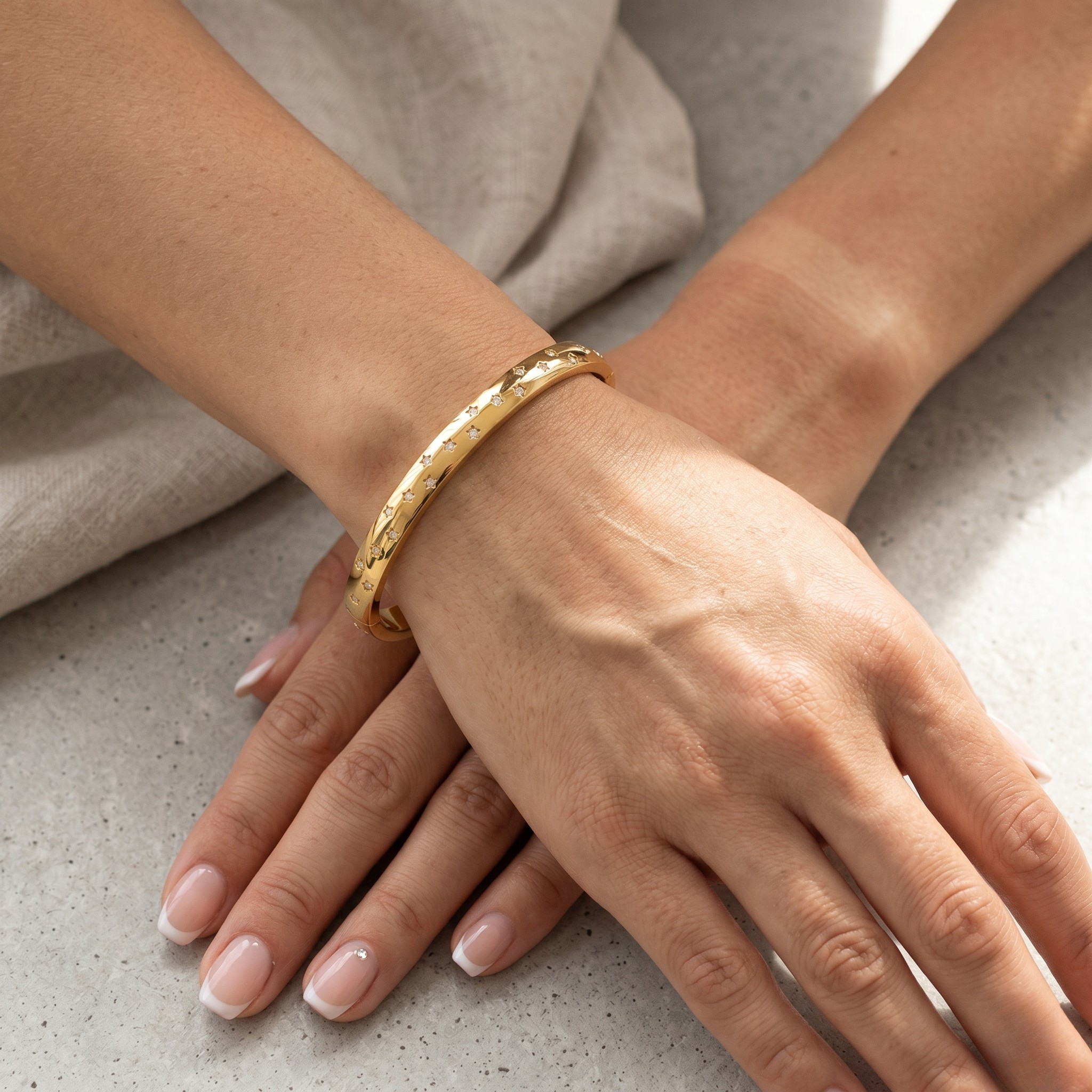 Gold Galaxy Crystal Bracelet on wrist with relaxed hands on a marble surface