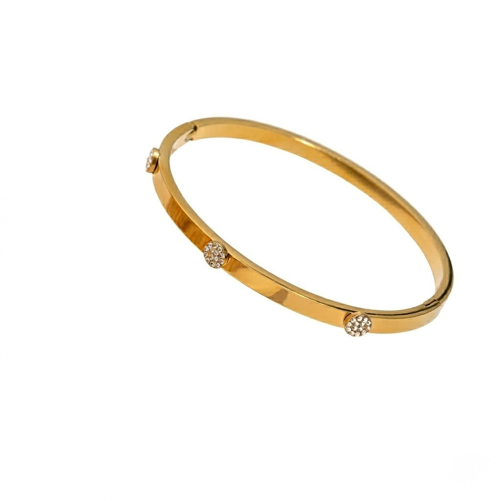 Gold bracelet with round diamond accents on a plain white background