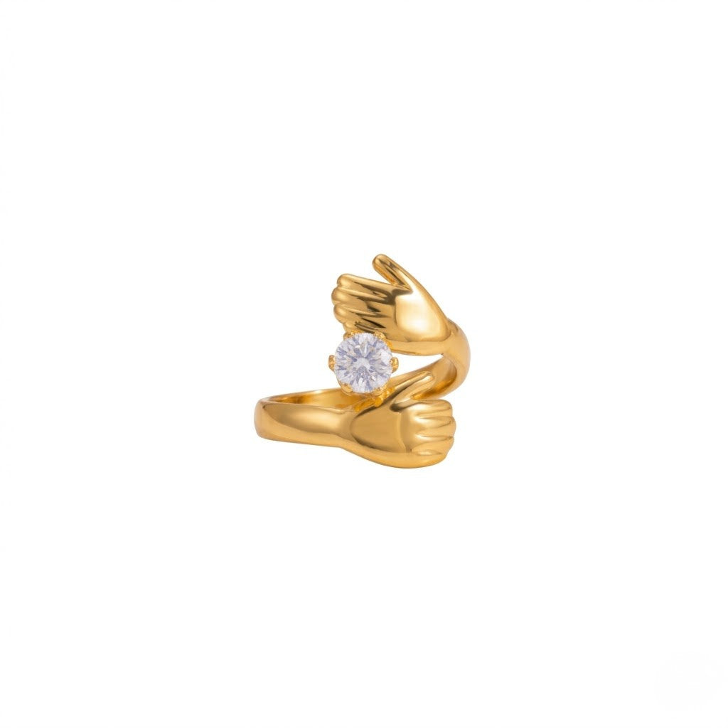 Gold ring with hands design holding a round diamond stone, unique embrace style.