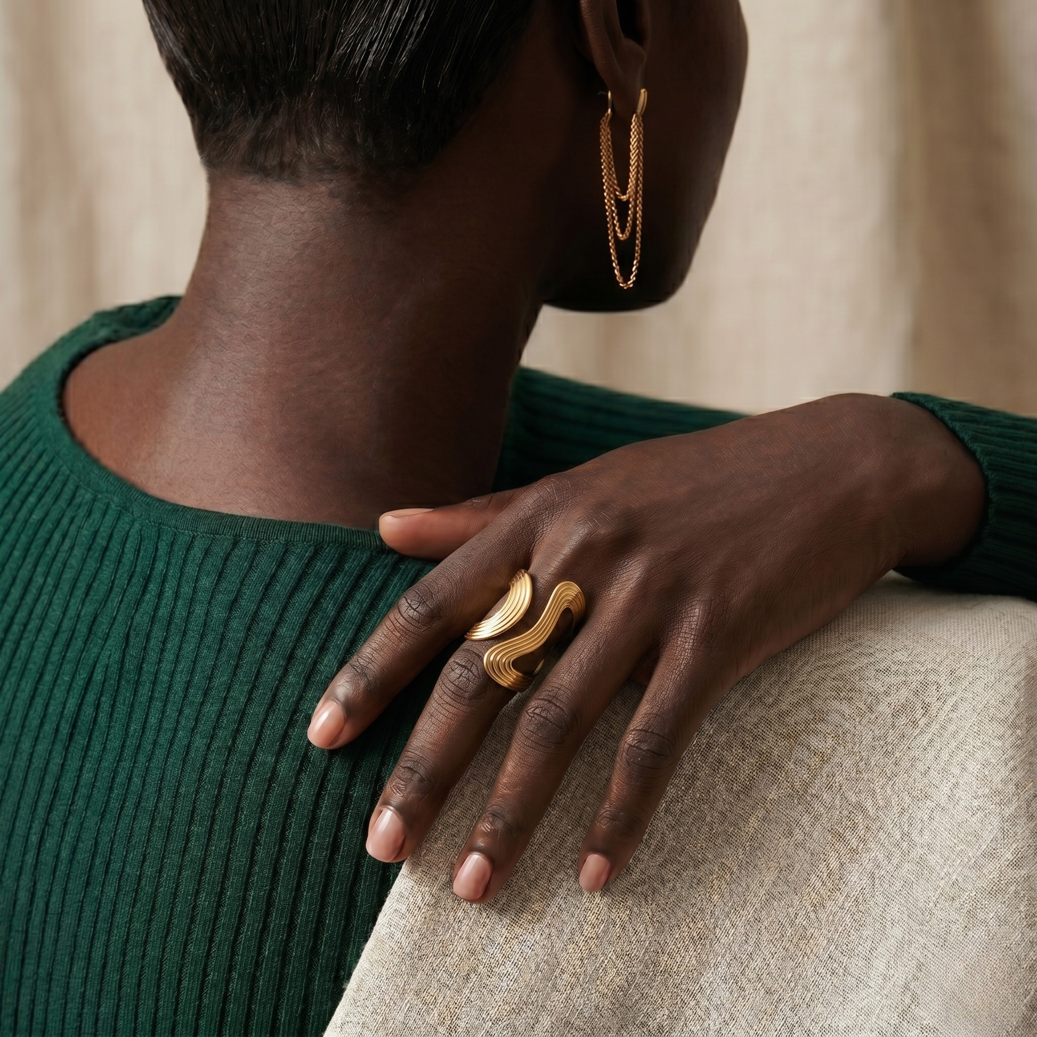 Gold 18k Circlet Ring on hand with green sweater, showcasing elegant design and artistic style in cozy setting.