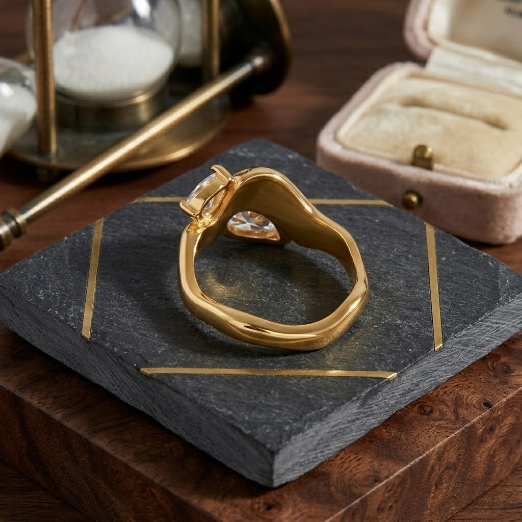 Gold Crested Twin Band ring on slate and wood with hourglass, open velvet box nearby