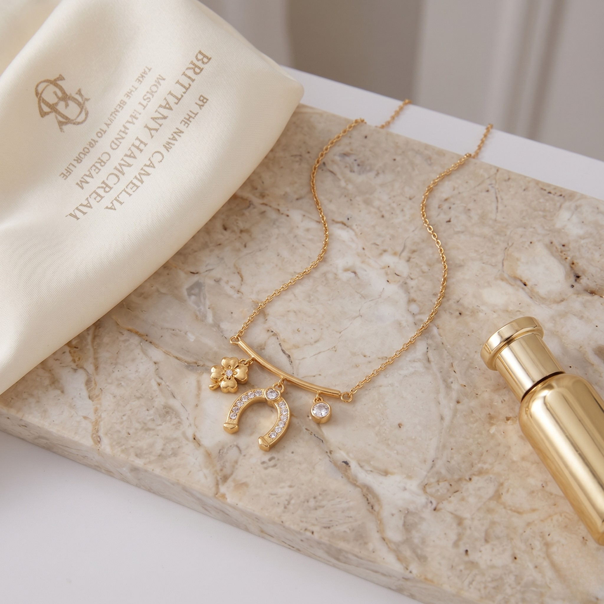 Gold necklace with clover, horseshoe, and diamond charms on a marble surface, elegant and luxurious style