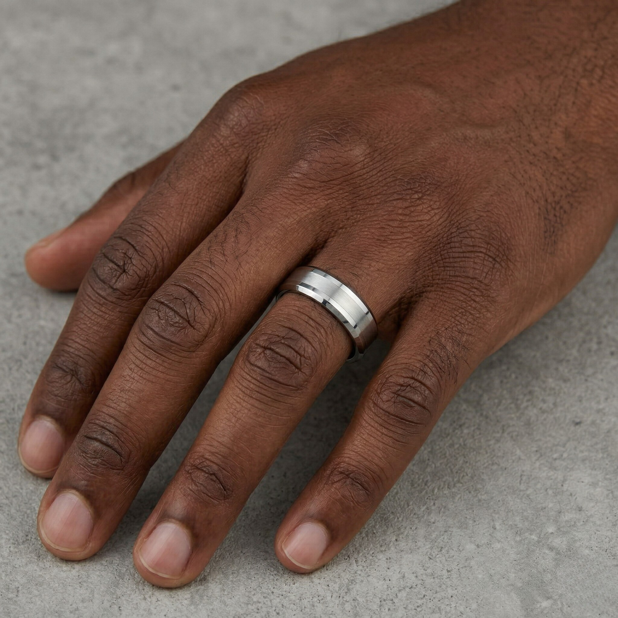 Hand wearing a silver ring on a gray background