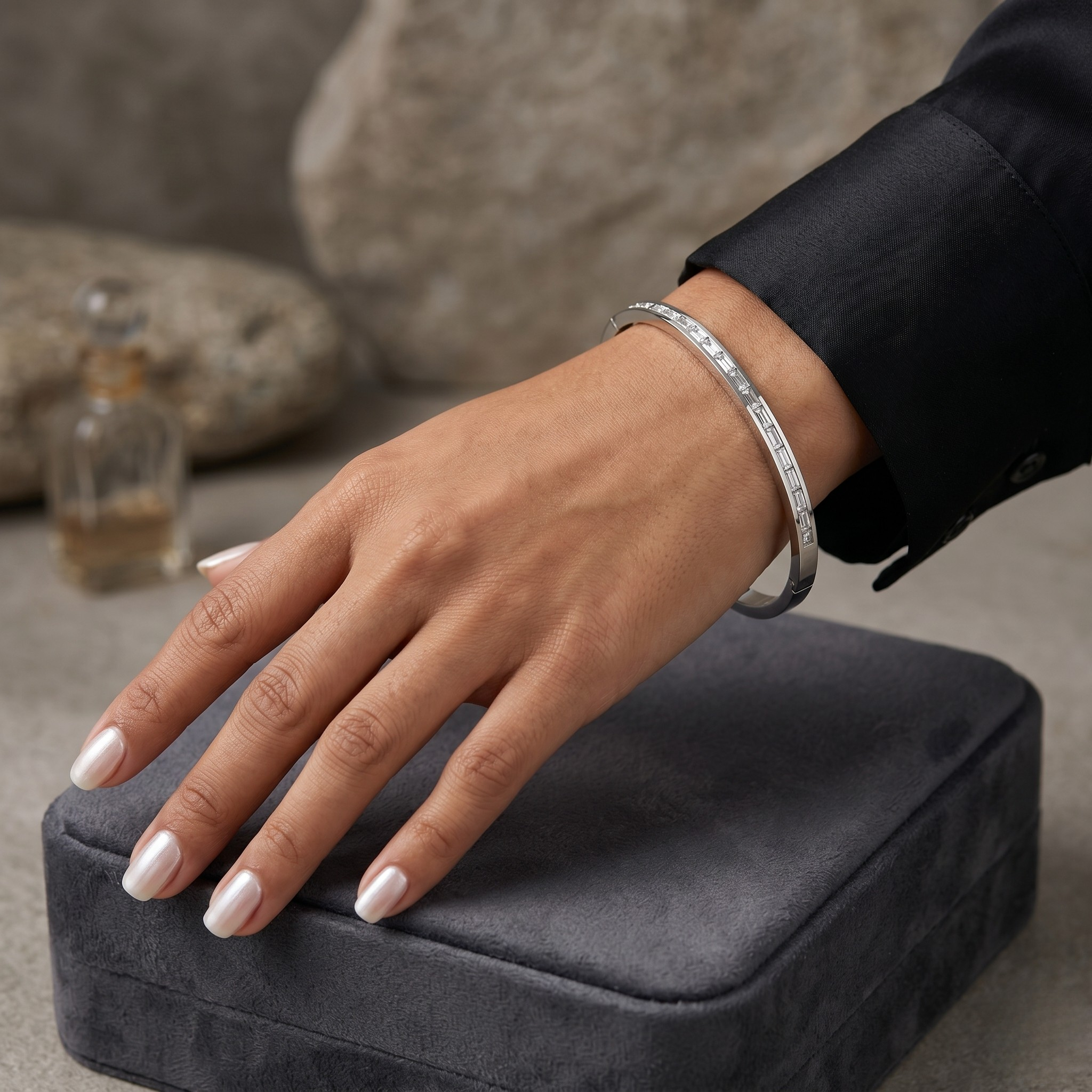 Silver channel stone bracelet on a model's wrist resting on a gray velvet box, showcasing minimalist elegance