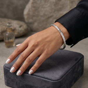 Silver channel stone bracelet on a model's wrist resting on a gray velvet box, showcasing minimalist elegance