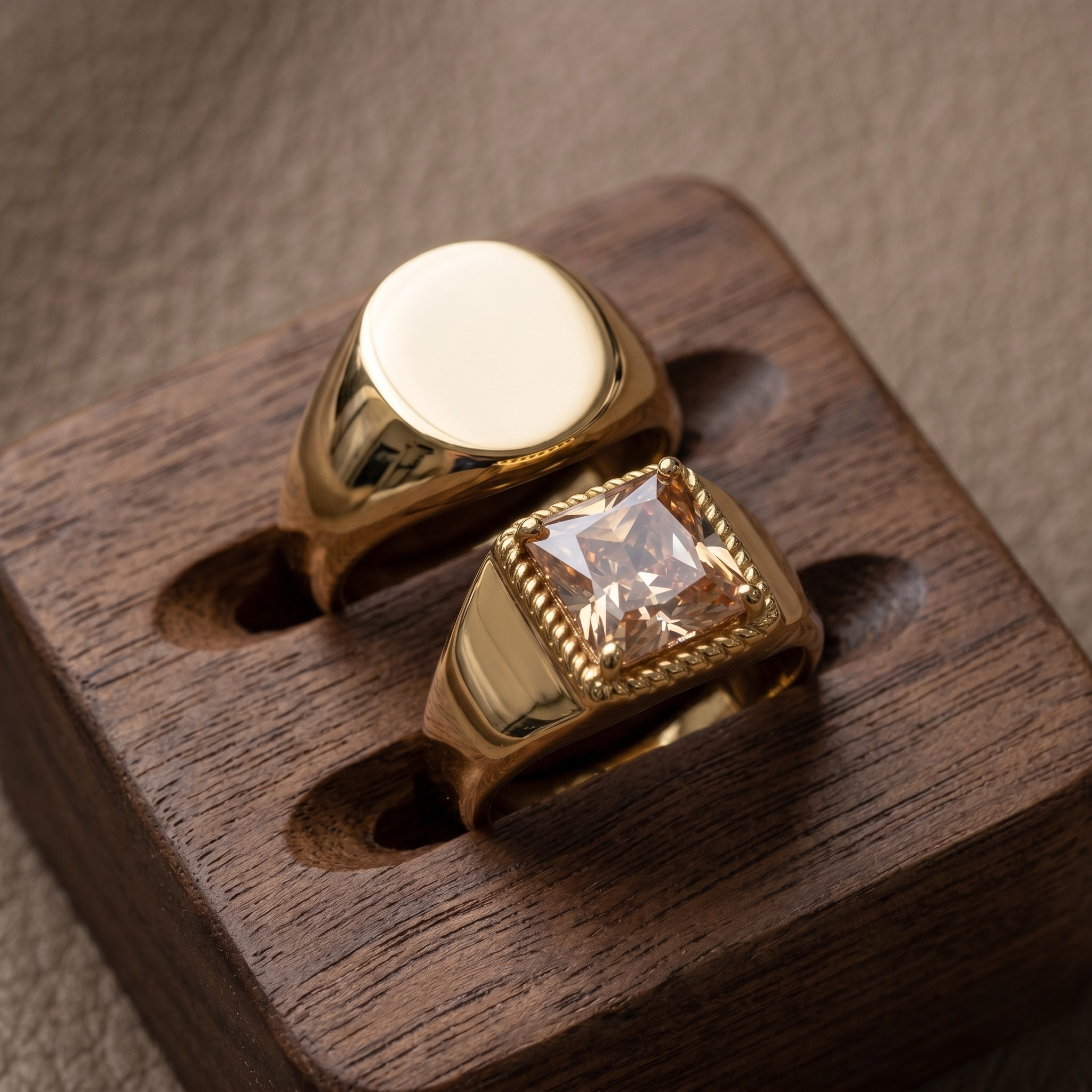 Gold essential signet band rings with smooth and square gemstone styles on a wooden display stand