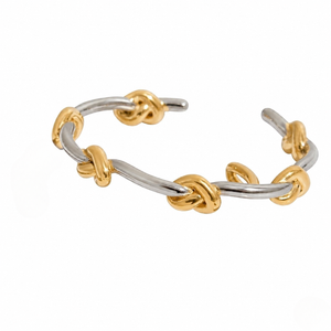 Duet Knot Bangle; two-tone silver and gold bracelet with knot accents, open cuff design.