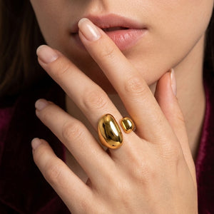 Gold Dune Open Ring with two polished beads worn on a woman's hand with manicured nails.