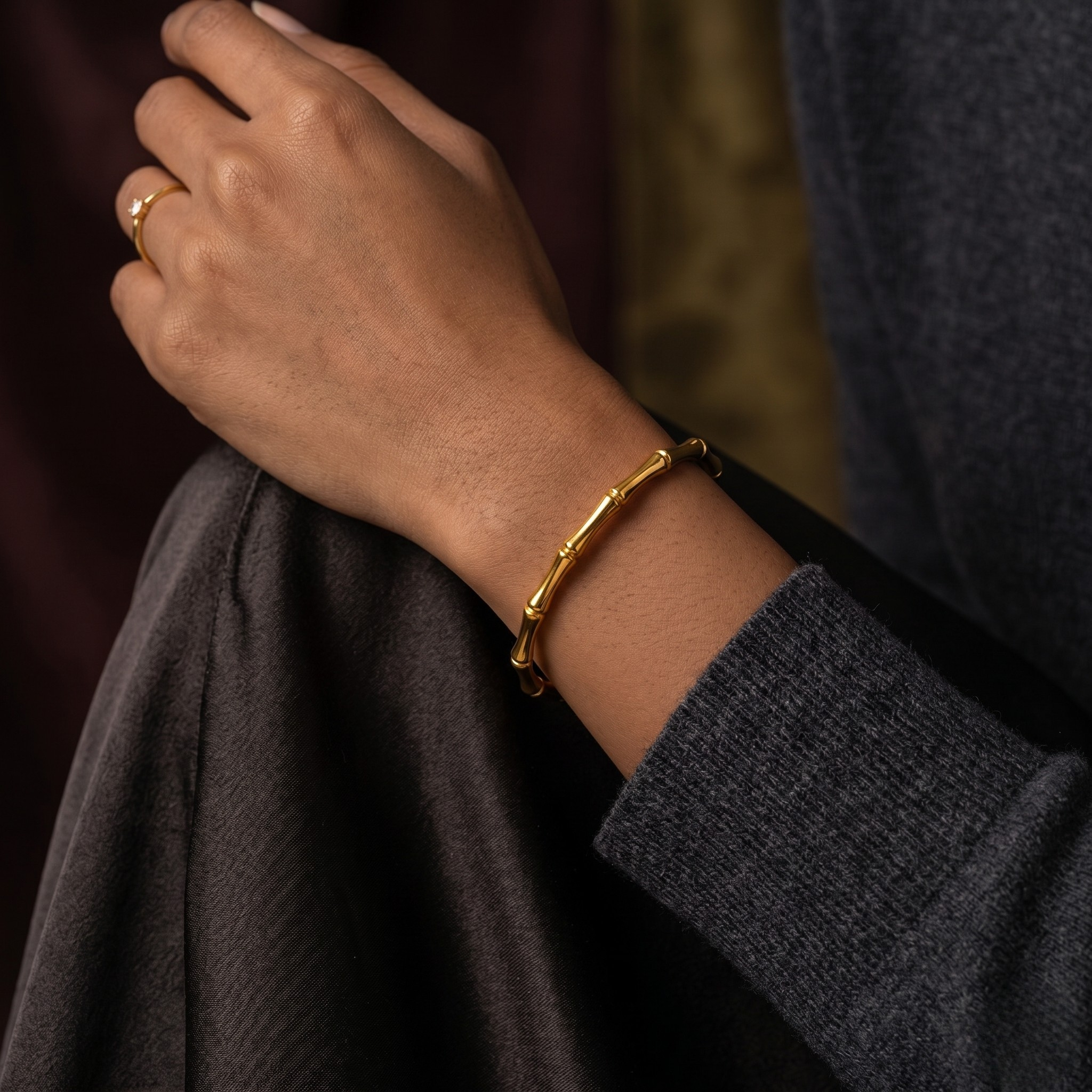 Sculpted Bamboo Bracelet in gold on wrist, paired with subtle gold ring, casual lifestyle setting.