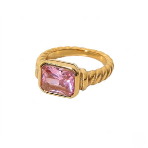 Gold ring with a twisted band and a rectangular pink gemstone in a bezel setting