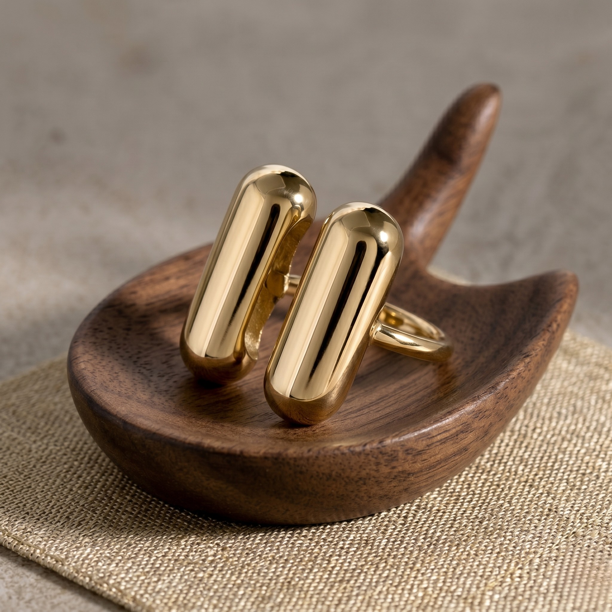 Twin Bar Ring in gold displayed on a wooden holder, showcasing sleek and modern design.