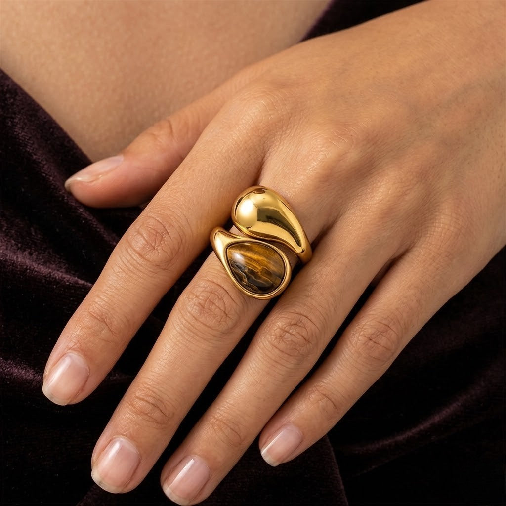 Gold molten teardrop ring with tiger's eye stone on a hand, showcasing elegant design and craftsmanship.