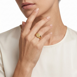 Woman wearing a gold signet ring on her finger, close-up, white shirt in background