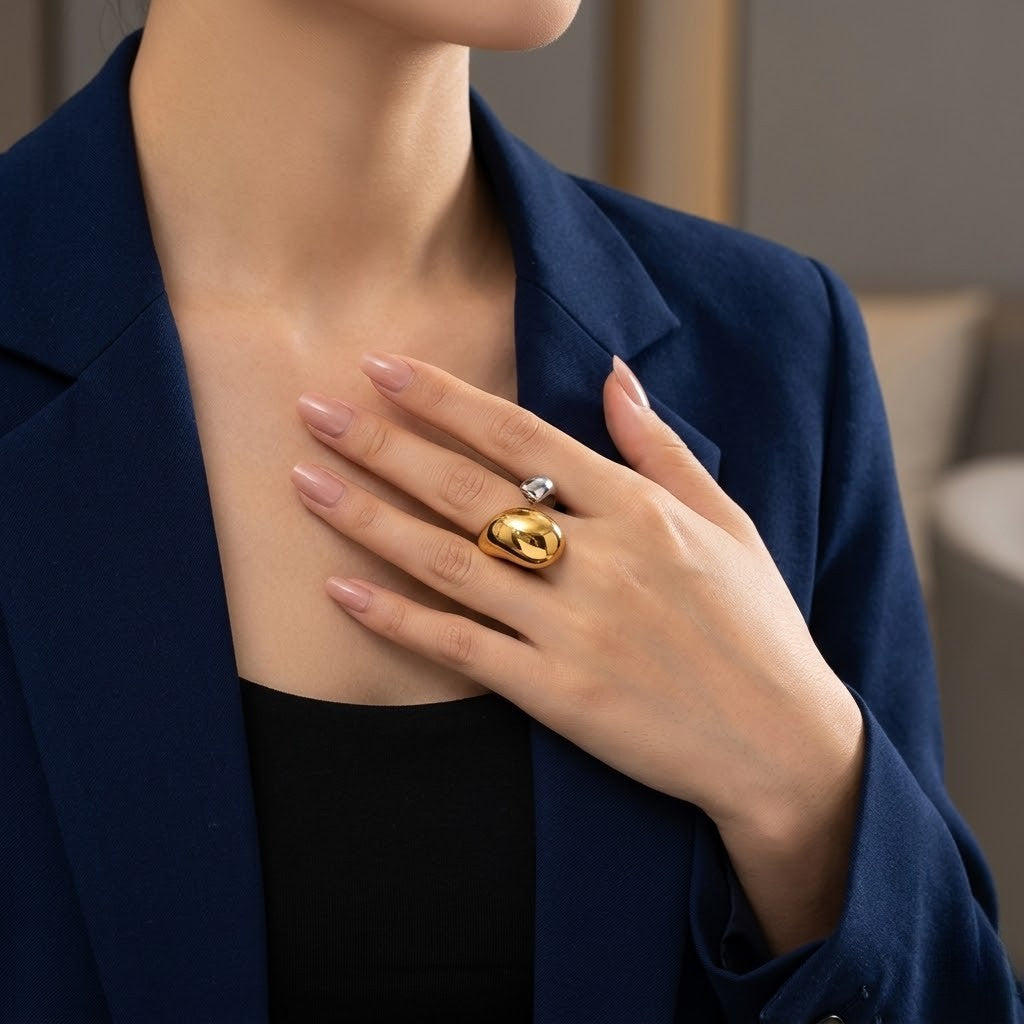 Gold and silver Vesper Duo Ring worn by a model in a blue blazer, hand on chest, oval and diamond details visible.