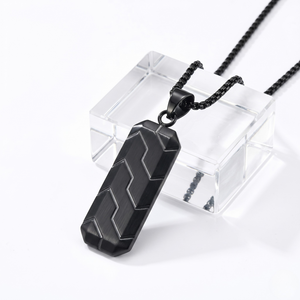 Black geometric pendant on chain with modern zigzag design, displayed on a clear stand.