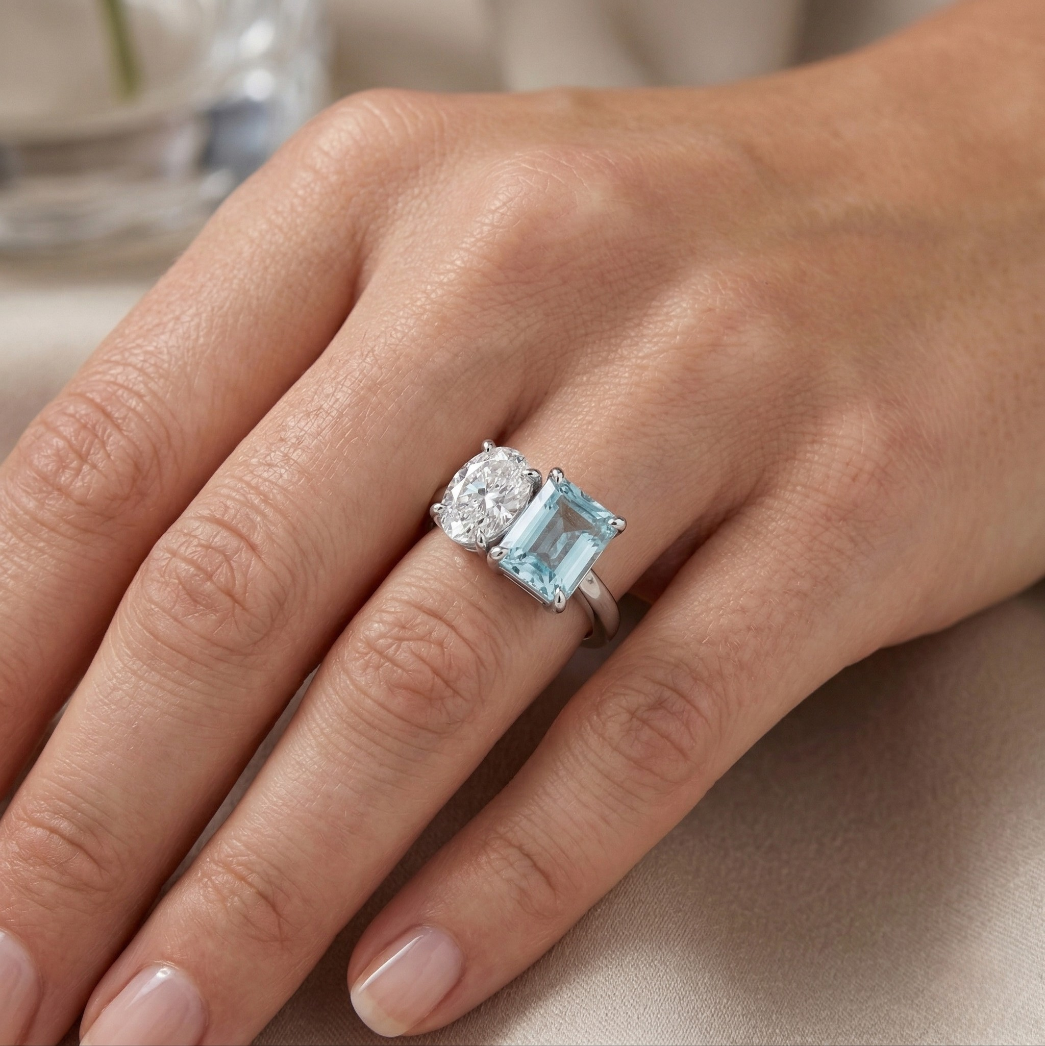 Hand with a 14K yellow gold moissanite ring featuring a large blue gemstone and clear stone on an elegant setting