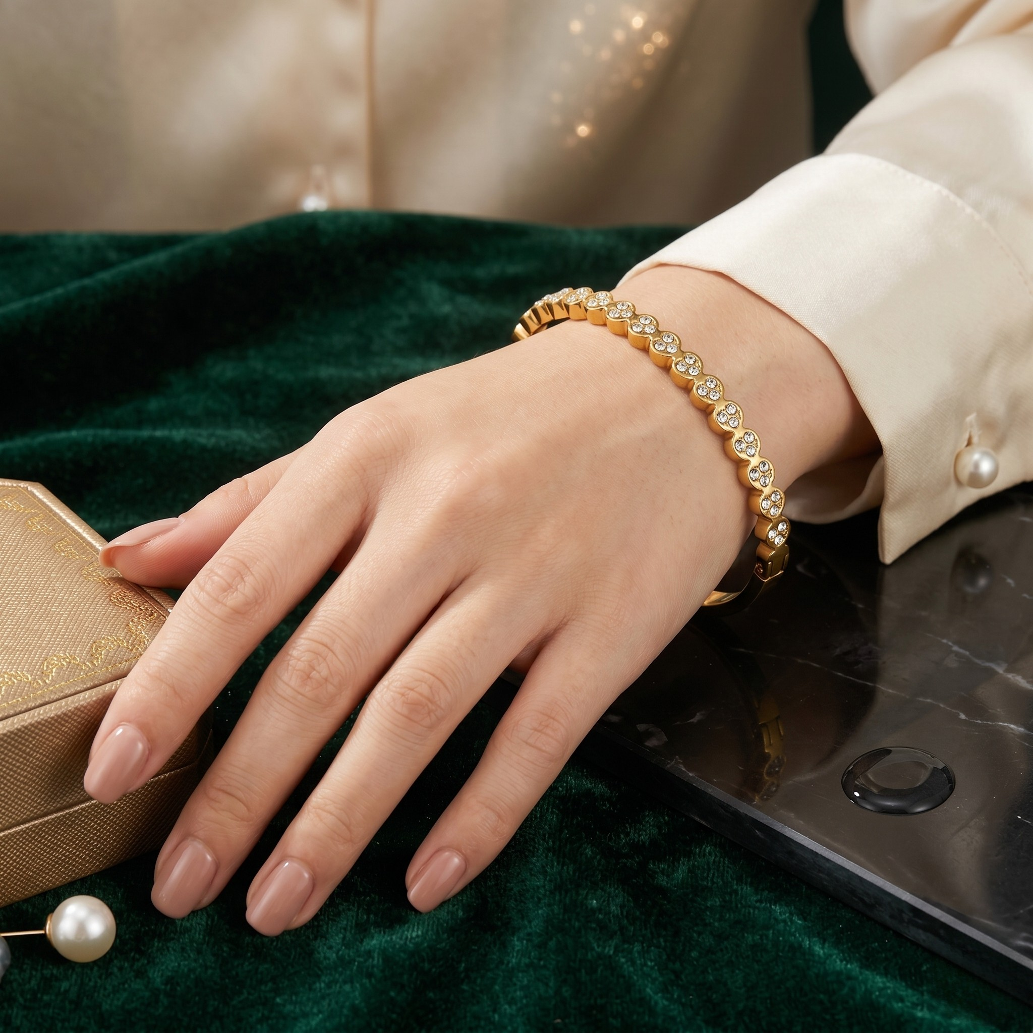 Stainless steel bangle with clustered stones on a woman's wrist, elegant setting with a velvet background.