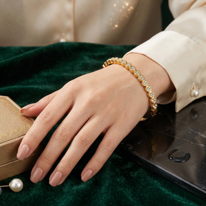 Stainless steel bangle with clustered stones on a woman's wrist, elegant setting with a velvet background.