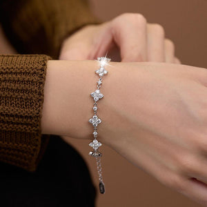 Silver bracelet with floral designs on a wrist against a brown background